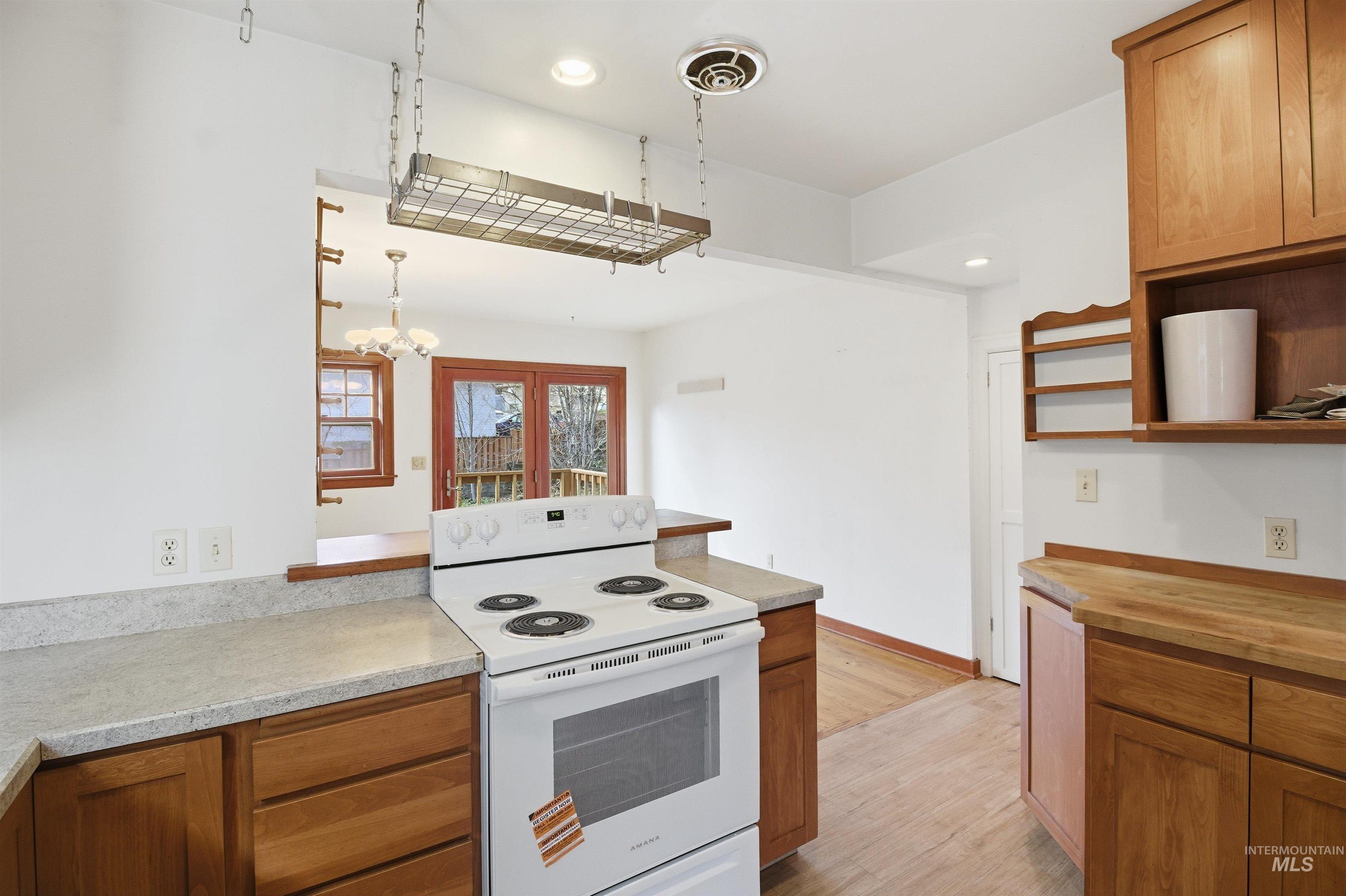 1117 East 6th Street Moscow, ID 83843 - Photo 17 of 46 Kitchen with white range with electric stovetop, wood finish cabinetry, a peninsula, light wood finished floors, and open shelves