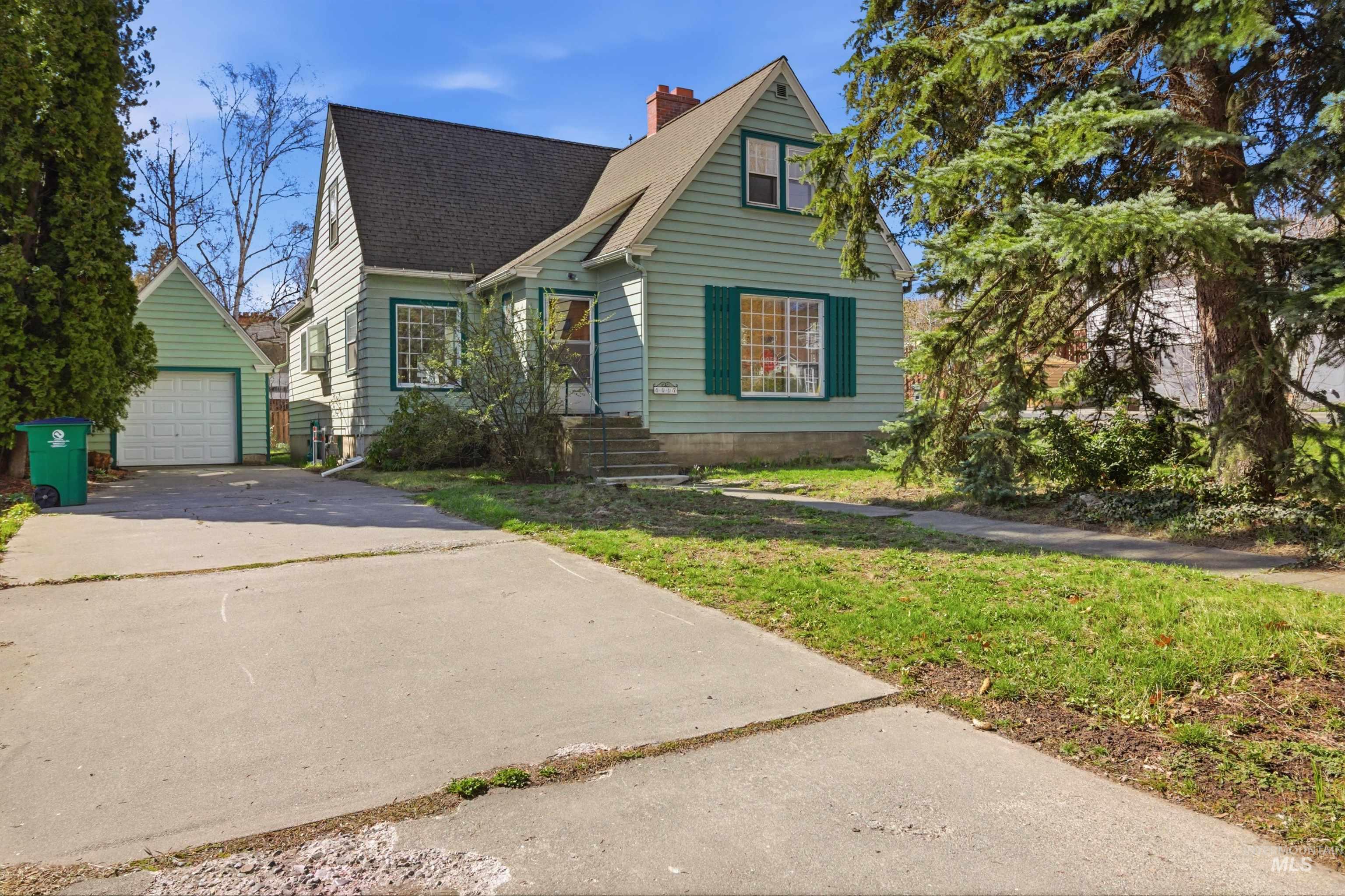1117 East 6th Street Moscow, ID 83843 - Photo 2 of 46 View of front facade featuring an outdoor structure, a chimney, a shingled roof, a detached garage, and concrete driveway