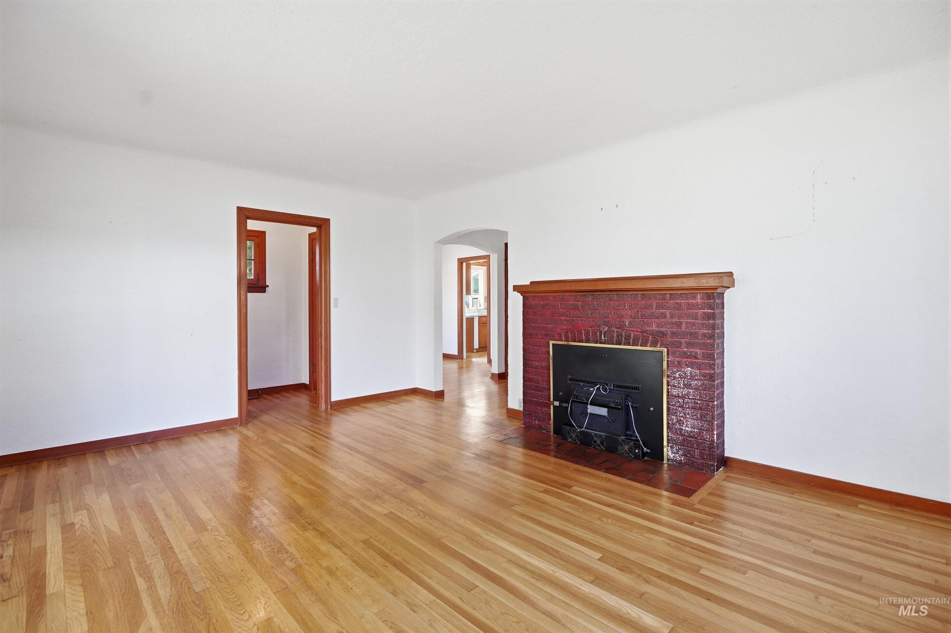 1117 East 6th Street Moscow, ID 83843 - Photo 24 of 46 Unfurnished living room with light wood-style floors, arched walkways, and a fireplace