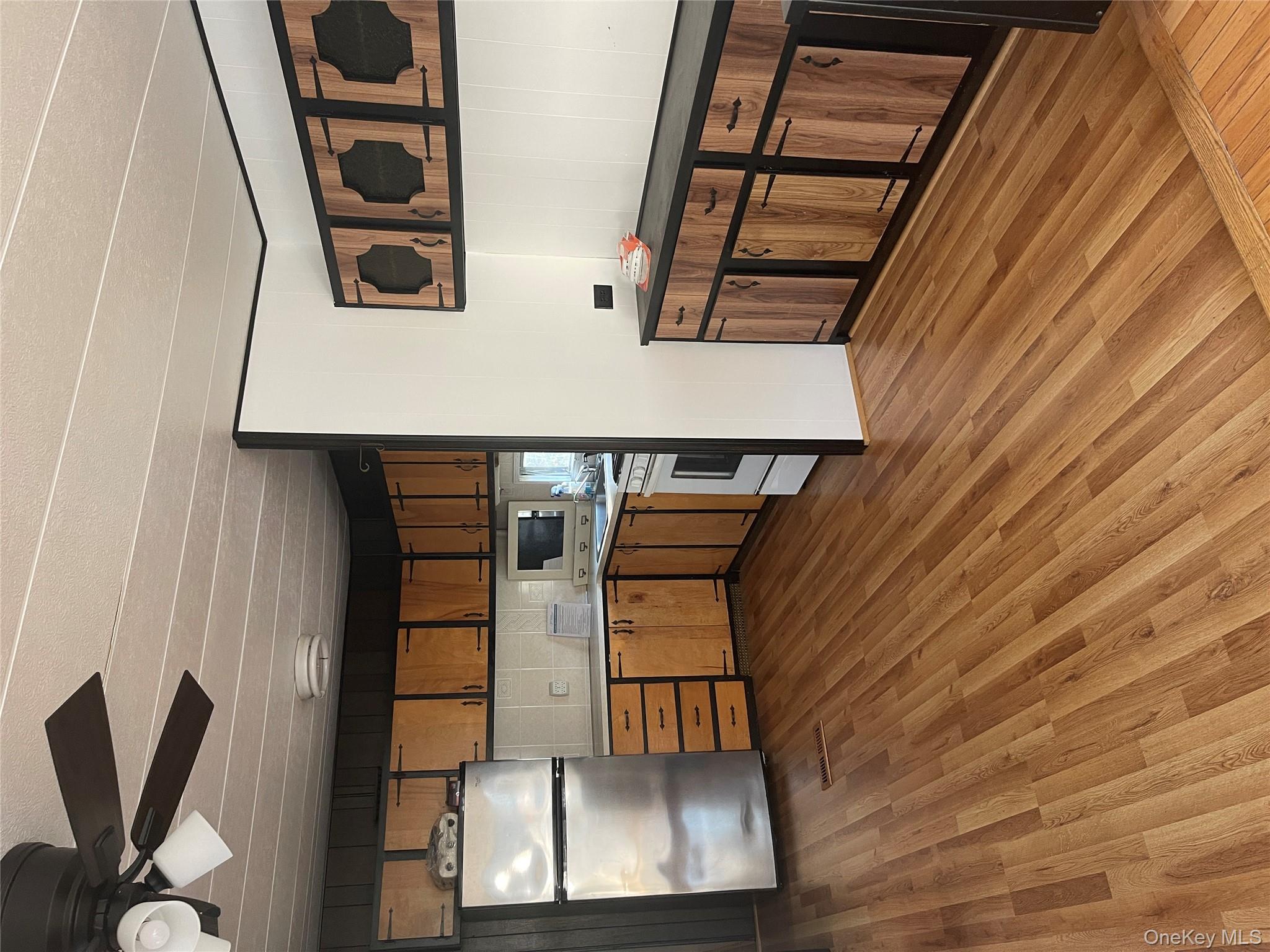 1661 Old Country Road, Unit 308 Riverhead, NY 11901 - Photo 2 of 10 a kitchen with stainless steel appliances wooden floors and wooden cabinets