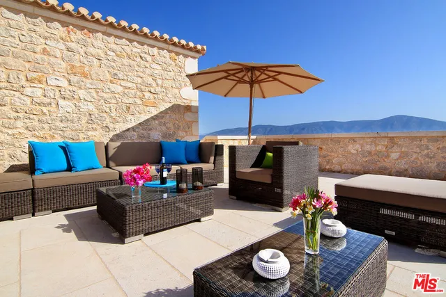 a view of a patio with couches table and chairs under an umbrella