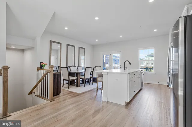 a large white kitchen with wooden floor and a sink