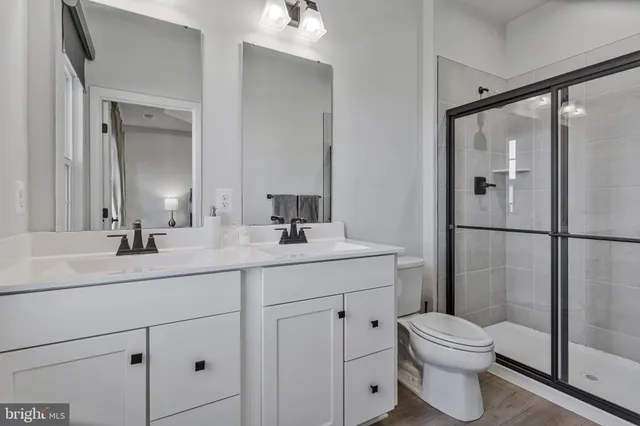 a bathroom with a toilet a sink a mirror and shower