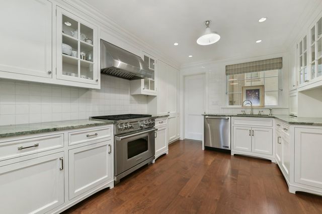 a kitchen with stainless steel appliances white cabinets and wooden floors
