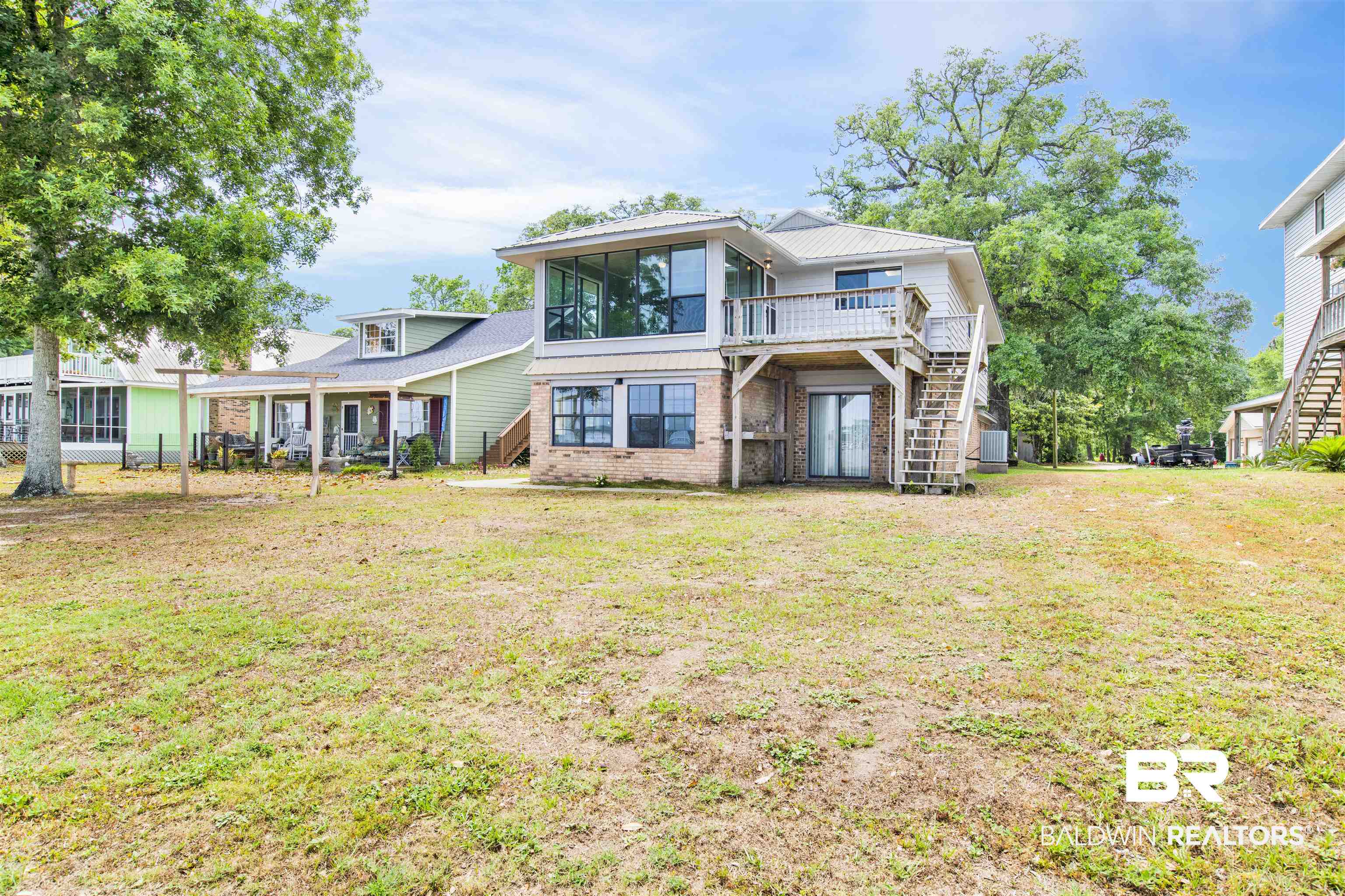 7411 Bay Road Mobile, AL 36605 - Photo 3 of 34 Rear view of property featuring stairway, brick siding, a yard, a patio, and a sunroom