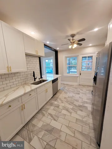 a large white kitchen with a sink and dishwasher a stove top oven with wooden floor