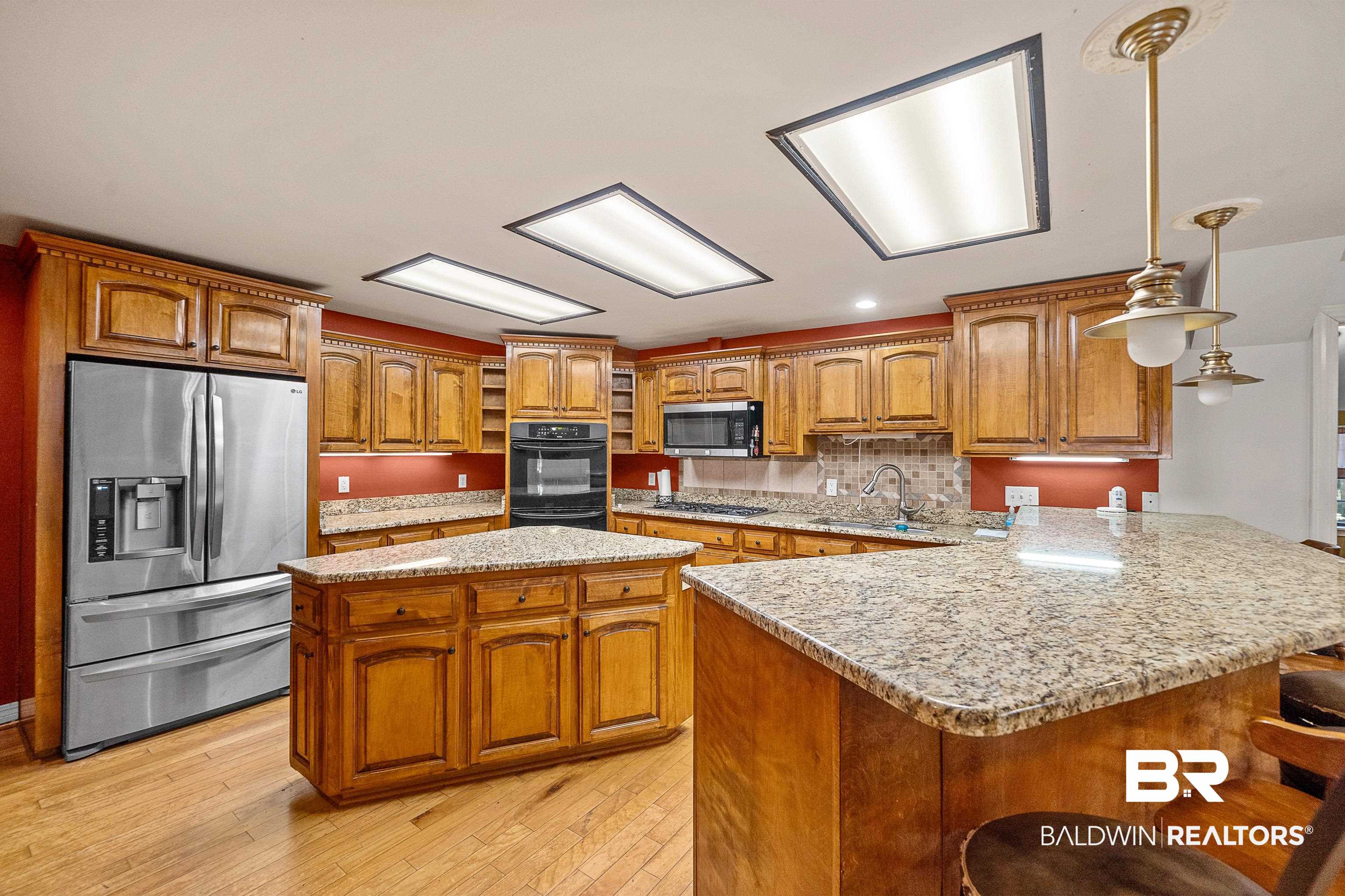 11528 Whitehouse Fork Road Bay Minette, AL 36507 - Photo 11 of 37 Kitchen with a kitchen island, a breakfast bar, appliances with stainless steel finishes, light stone countertops, and hanging light fixtures