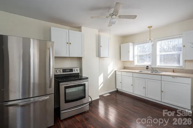 a kitchen with granite countertop stainless steel appliances a refrigerator cabinets and wooden floor