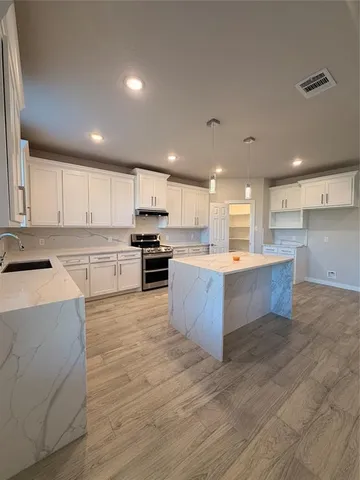 a large kitchen with stainless steel appliances granite countertop a stove a sink dishwasher and a refrigerator with wooden floor