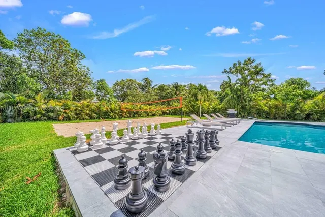 a view of swimming pool with seating space and trees in the background