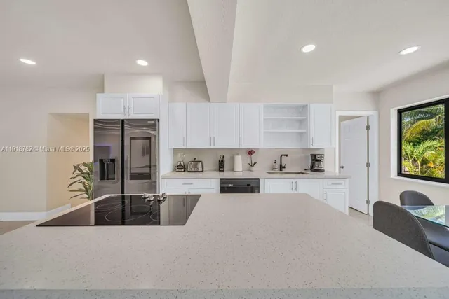 a large kitchen with kitchen island a large counter top space a sink stainless steel appliances and cabinets