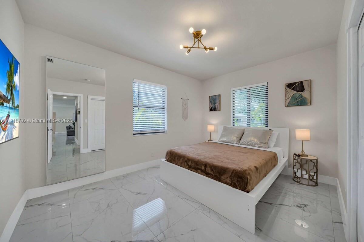 305 Northwest 124th Street North Miami, FL 33168 - Photo 24 of 41 a spacious bedroom with a large bed and a chandelier