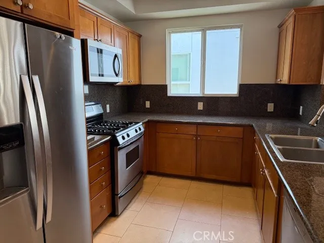 a kitchen with stainless steel appliances granite countertop a refrigerator a sink and a stove