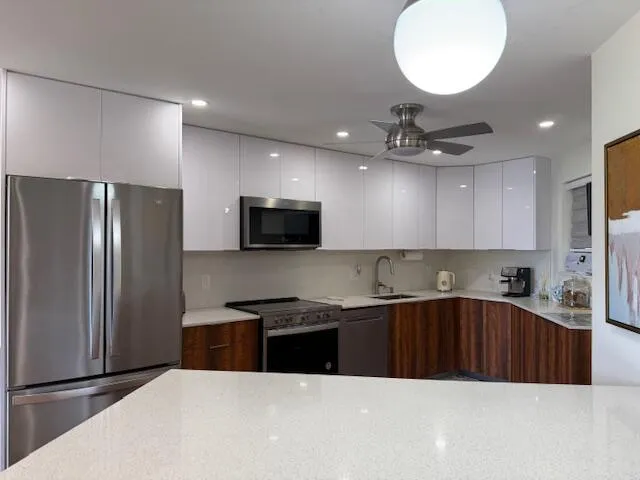 a kitchen with stainless steel appliances a sink a stove a refrigerator and cabinets