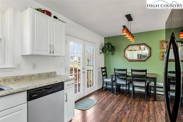 a kitchen with stainless steel appliances granite countertop a stove a sink dishwasher and a dining table with wooden floor