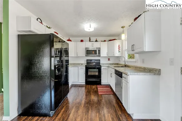 a kitchen with stainless steel appliances granite countertop a refrigerator a stove and a sink
