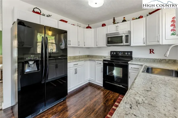 a kitchen with stainless steel appliances granite countertop a stove a sink and a microwave
