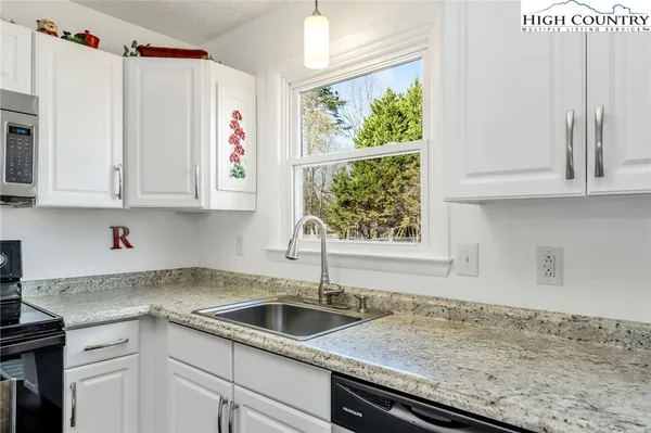 a kitchen with stainless steel appliances granite countertop a sink and a white cabinets