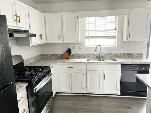 a kitchen with granite countertop white cabinets and a stove