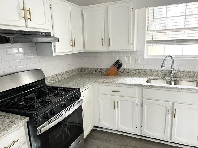 a kitchen with granite countertop white cabinets and white appliances