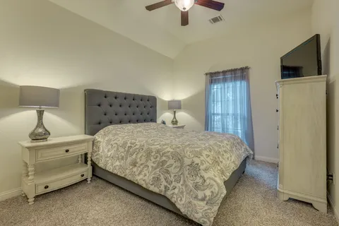 a bedroom with a bed and a flat tv screen on a dresser