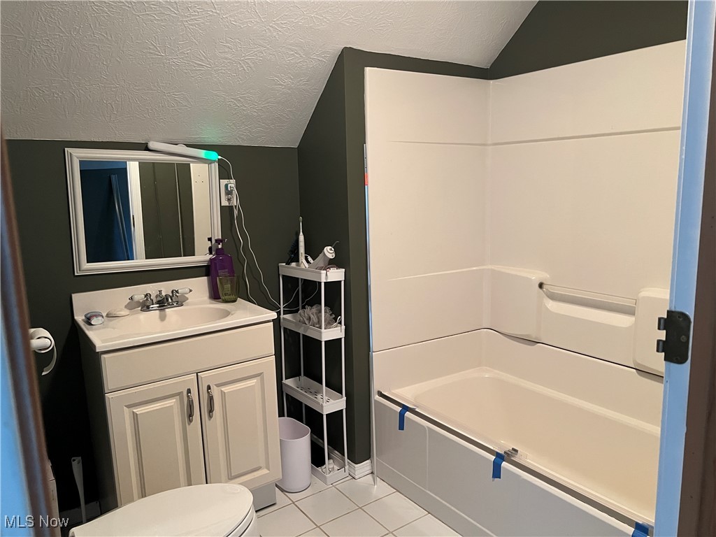 5912 Coen Road Vermilion, OH 44089 - Photo 18 of 28 Full bathroom with a textured ceiling, light tile patterned floors, vanity, lofted ceiling, and shower / washtub combination
