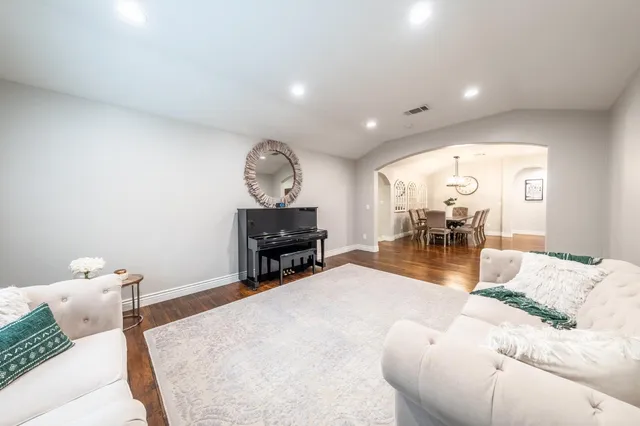 a room with stainless steel appliances kitchen island granite countertop a dining table chairs and view of living room