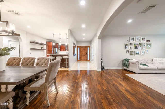 a dining hall with stainless steel appliances kitchen island granite countertop a table chairs and a view of living room