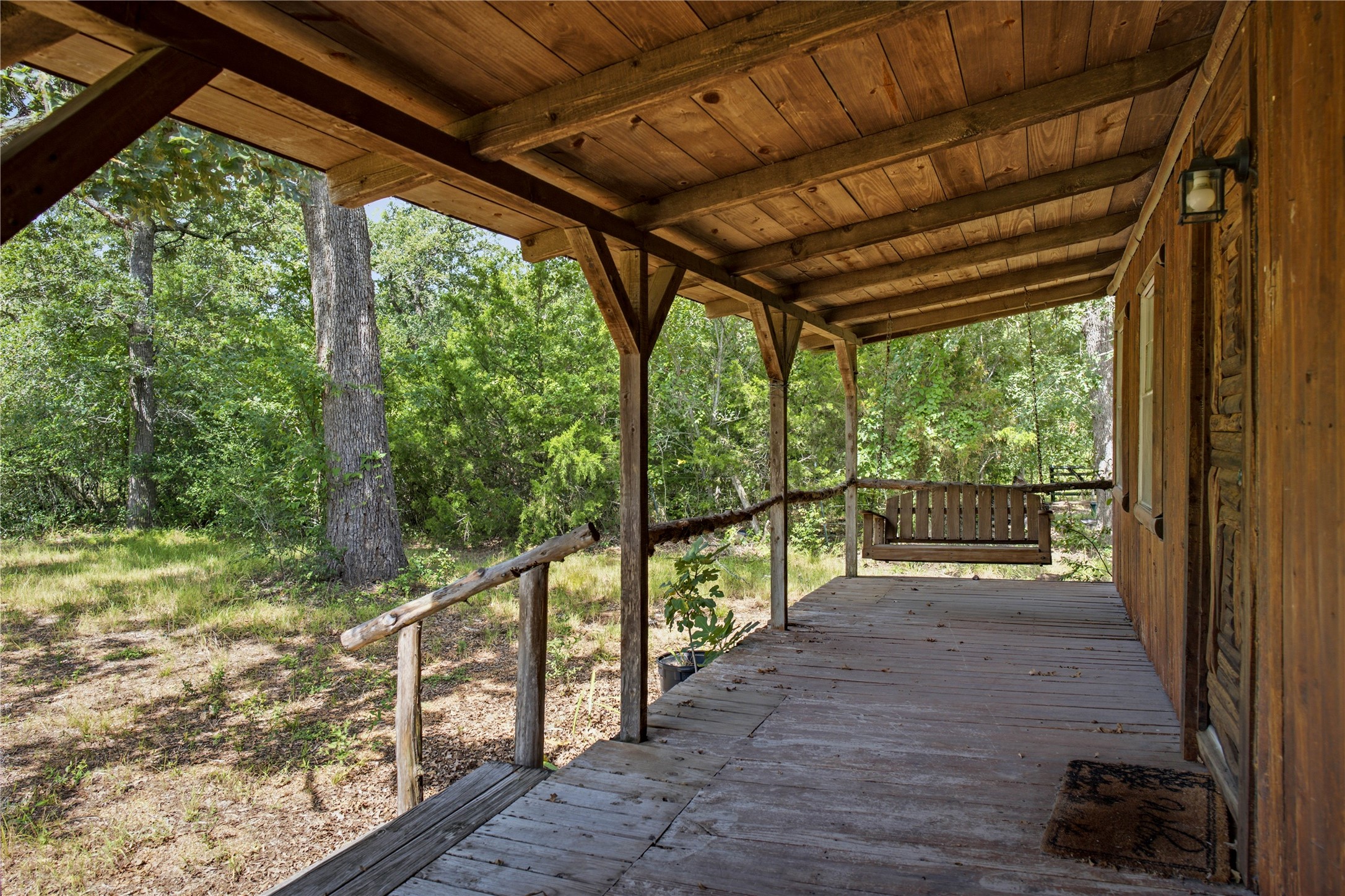7221 West Old Lockhart Road Muldoon, TX 78949 - Photo 12 of 38 A rustic covered wooden porch looks out onto a serene wooded yard.