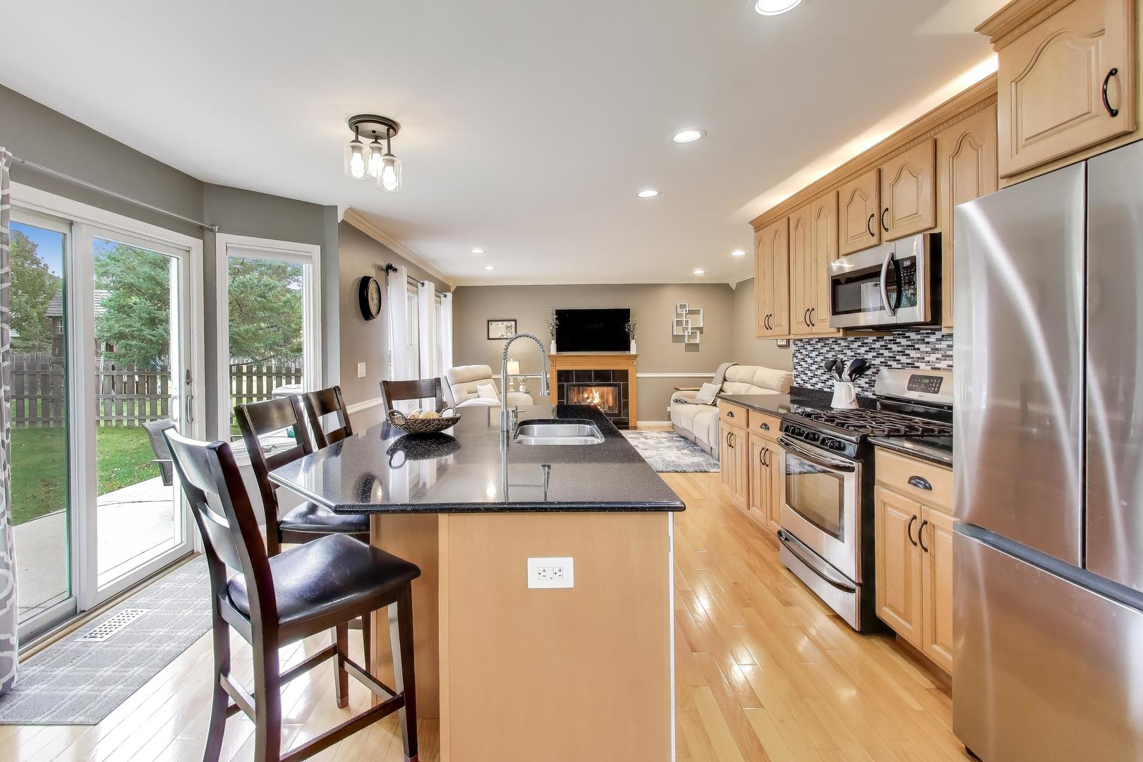 470 Country Place Lindenhurst, IL 60046 - Photo 8 of 29 a kitchen with stainless steel appliances granite countertop a stove a refrigerator a kitchen island a table and chairs