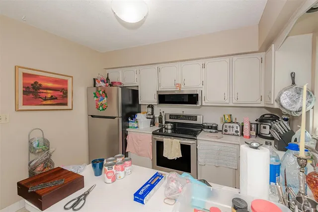 a kitchen with stainless steel appliances kitchen island granite countertop a sink dishwasher stove and refrigerator