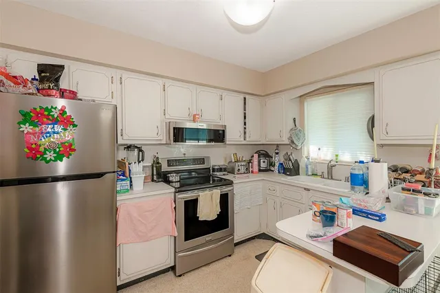 a kitchen with stainless steel appliances a stove a sink refrigerator and a cabinets