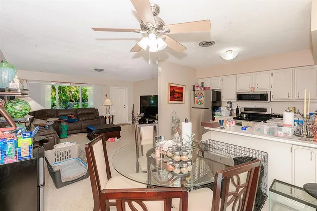 a kitchen with stainless steel appliances kitchen island granite countertop a dining table chairs refrigerator and microwave