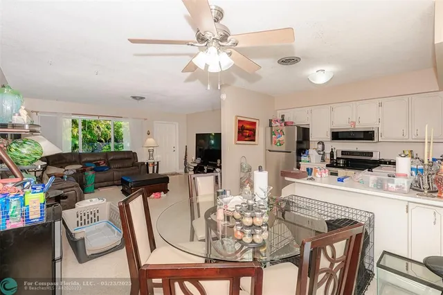 a kitchen with stainless steel appliances kitchen island granite countertop a dining table chairs refrigerator and microwave