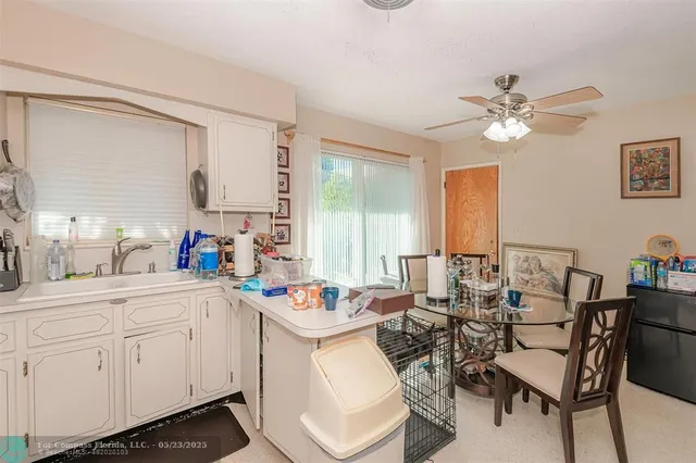 a very nice looking dining room with kitchen island a large window a sink and white cabinets