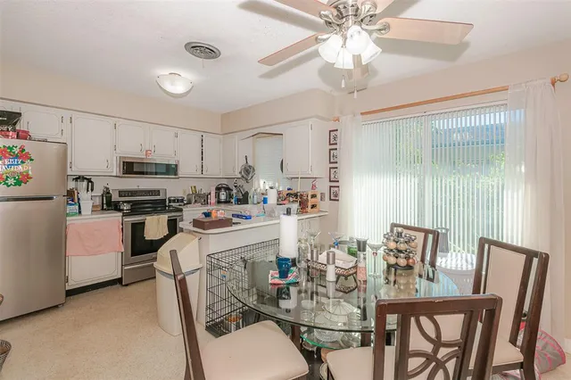 a kitchen with a dining table chairs stainless steel appliances and cabinets