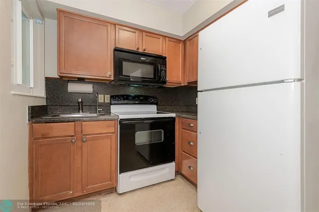 a kitchen with stainless steel appliances granite countertop white cabinets a microwave a sink and a refrigerator
