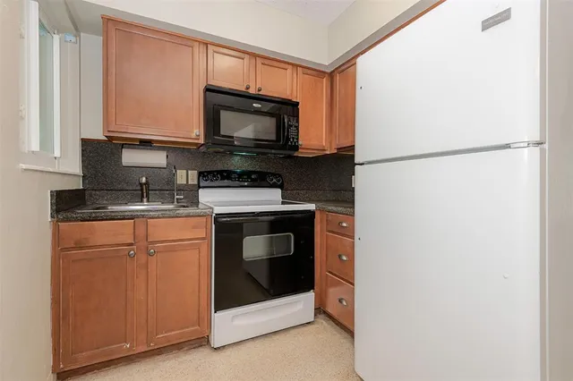 a kitchen with stainless steel appliances granite countertop white cabinets a microwave a sink and a refrigerator