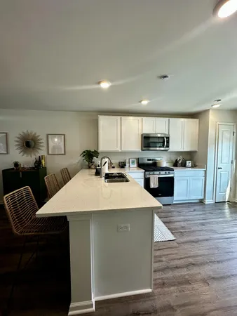 a large white kitchen with wooden floors and stainless steel appliances