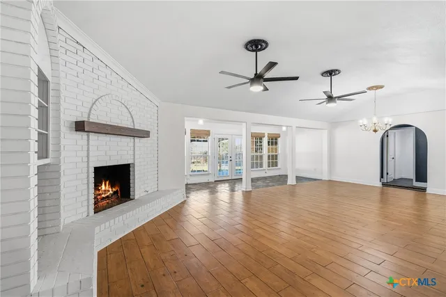 a view of an empty room with a fireplace and wooden floor