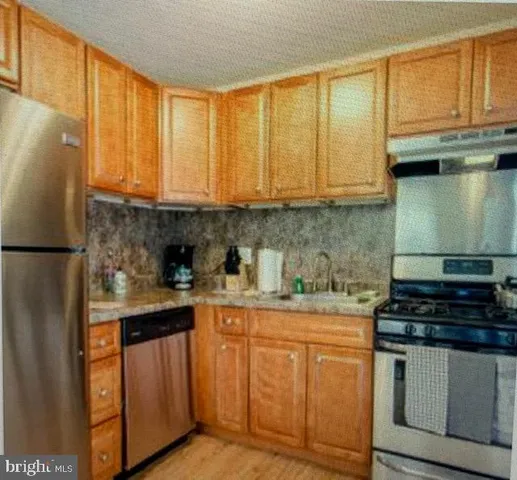 a kitchen with stainless steel appliances granite countertop a sink a stove and a refrigerator