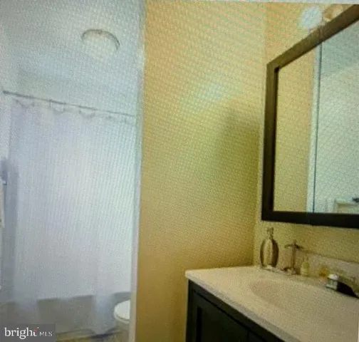 a bathroom with a granite countertop sink and a toilet