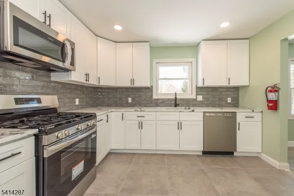 a kitchen with granite countertop cabinets stainless steel appliances and a window