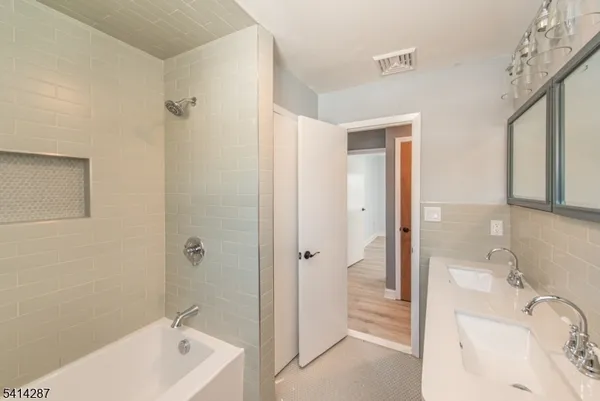 a bathroom with a tub sink shower and two mirror