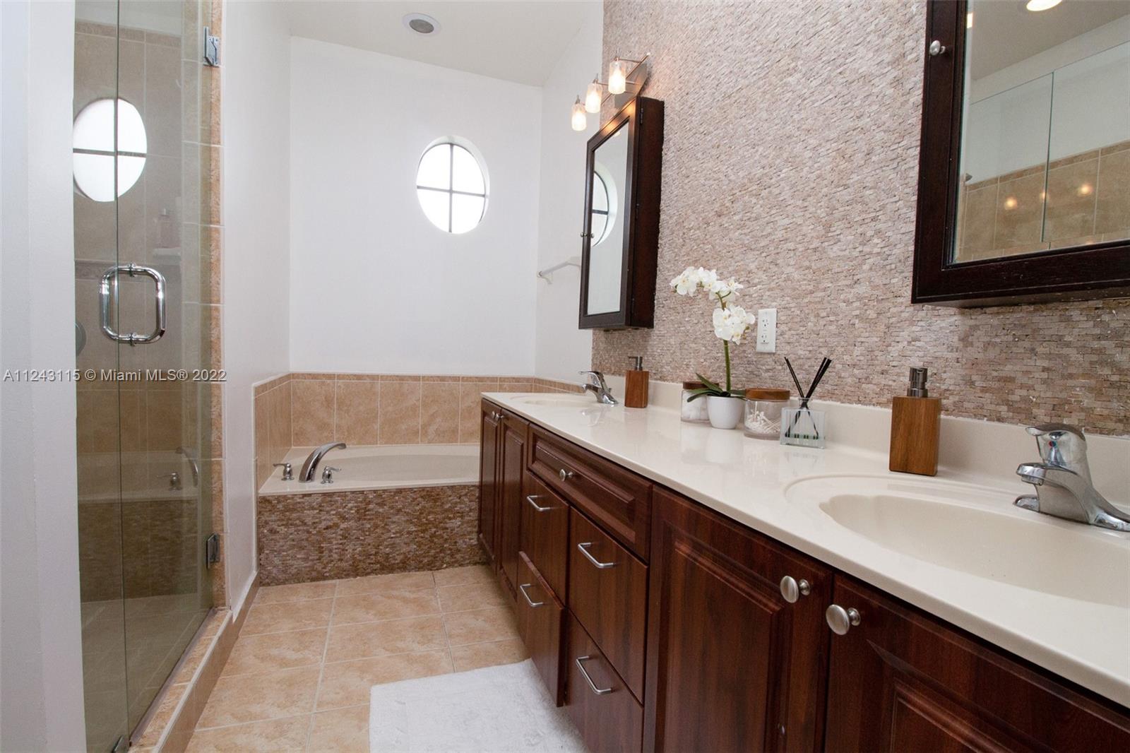22737 Southwest 89th Path Cutler Bay, FL 33190 - Photo 6 of 27 a bathroom with a double vanity sink a mirror and a bathtub