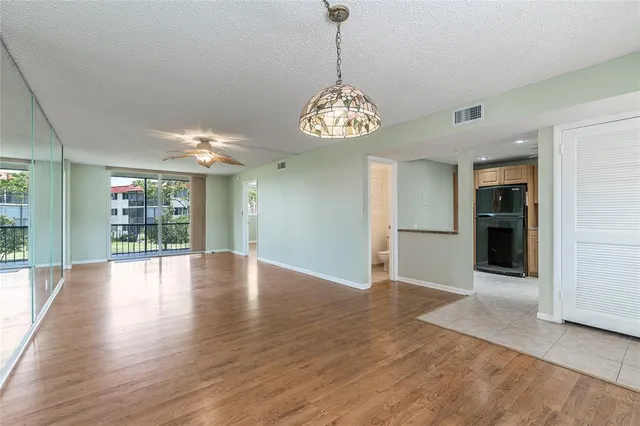 an empty room with wooden floor windows and kitchen view