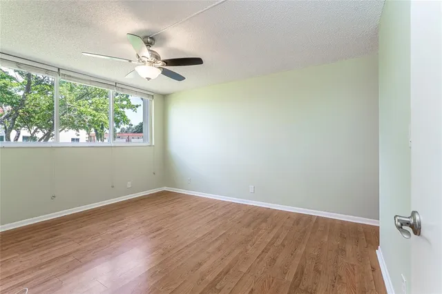an empty room with wooden floor fan and windows