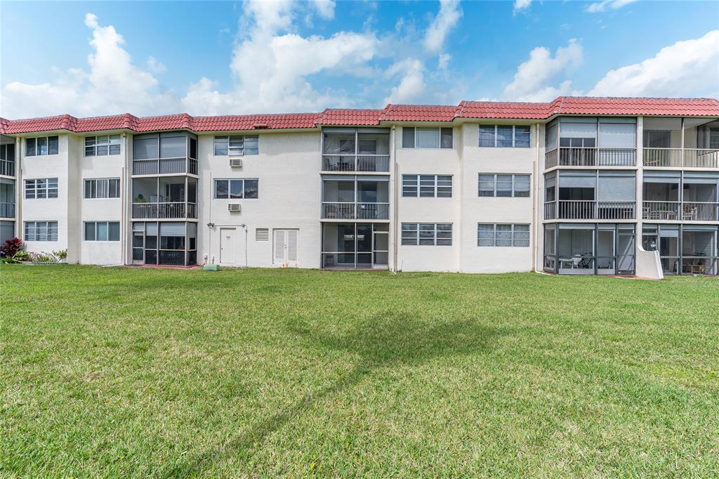 9720 South Hollybrook Lake Drive, Unit 205 Pembroke Pines, FL 33025 - Photo 19 of 57 a view of a large building with a big yard and large trees