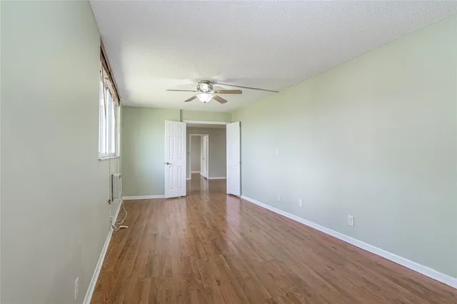 an empty room with wooden floor and chandelier fan