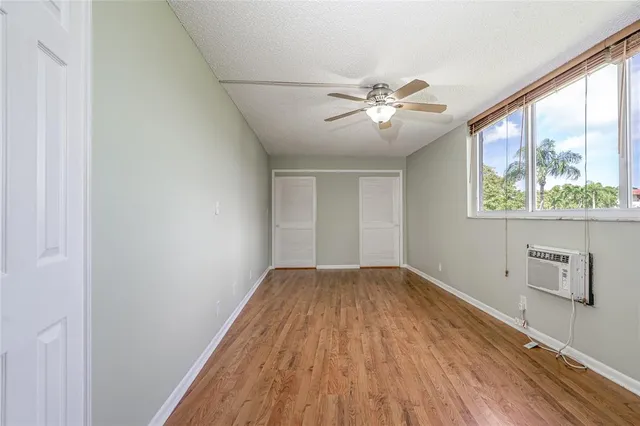 a view of empty room with wooden floor and fan